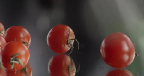 Cherry tomatoes fall from side on a mirror surface Stock Footage 200255250