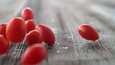 Cherry tomatoes falling and rolling on a table. Slow Motion. Stock Footage 84930802