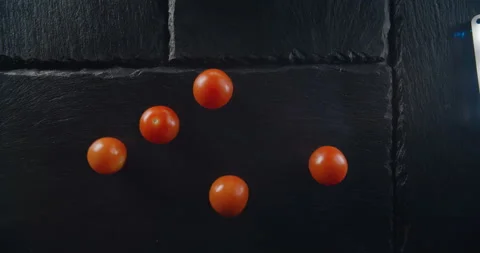Cherry tomatoes falling and rolling on table in slow motion. Stock Footage 101283782