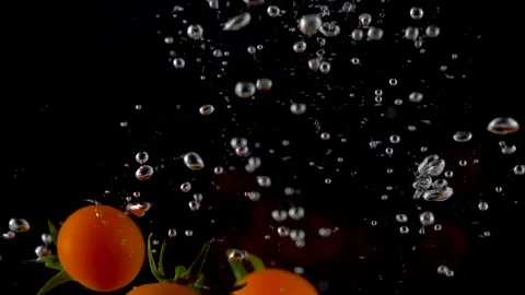 Cherry tomatoes falling into clear water with big splash on black background. Stock-Footage 150567159