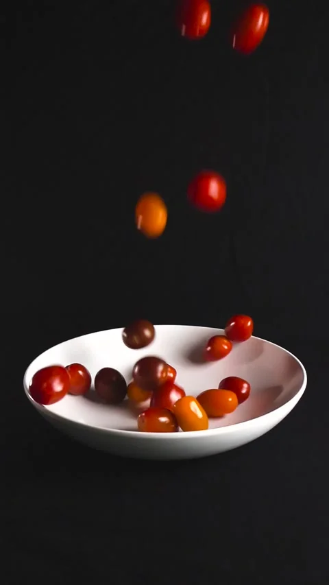 Cherry tomatoes falling into a white bowl in slow motion Stock Footage 340148085