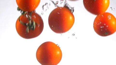 Cherry tomatoes falls into water and make bubbles slow motion Stock Footage 122178255