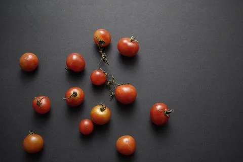 Cherry tomatoes flat lay on black grunge texture abstract background. Stock Photos