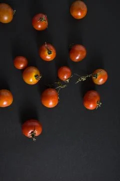 Cherry tomatoes flat lay on black grunge texture abstract background. Stock Photos