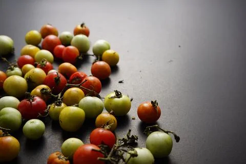 Cherry tomatoes flat lay on black grunge texture abstract background. Stock Photos