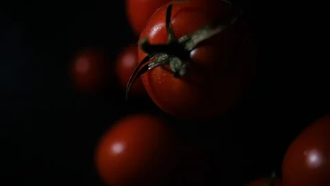 Cherry tomatoes flies after being exploded against black background. Stock Footage 123313098