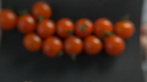Cherry tomatoes fly beautifully on black background Stock Footage 97884139