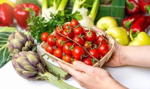 Cherry tomatoes in hands on background of vegetables Stock Photos