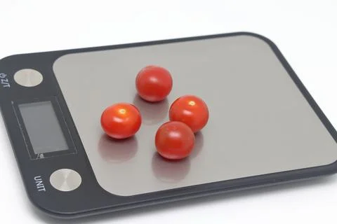 Cherry tomatoes on a kitchen scale, selective focus. Expensive disposable t.. Stock Photos