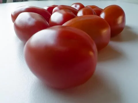 Cherry tomatoes lying on a white table Stock Photos