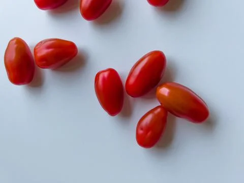Cherry tomatoes lying on a white table Stock Photos