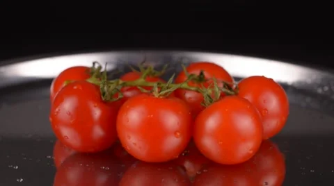 Cherry tomatoes on metallic plate rotating on black background Stock Footage 65227850