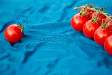 Cherry tomatoes over blue textile with copy space Stock Photos