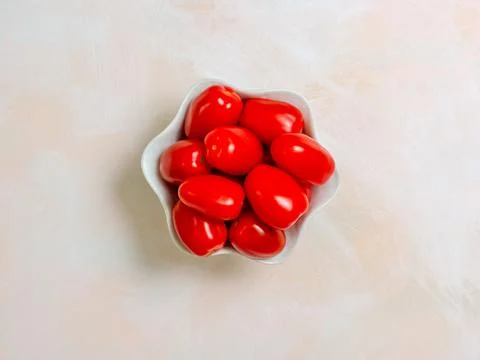 Cherry tomatoes red tiny in a white bowl on a light background, photo from .. Stock Photos