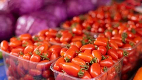 Cherry Tomatoes in see-through plastic containers on display in grocery. Isol Foto stock