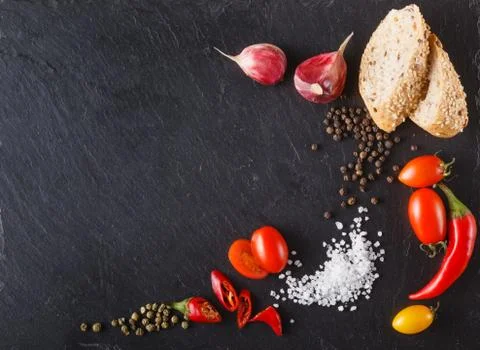 Cherry tomatoes on slate with sliced bread, black and green pepper, salt. Pla Stock Photos