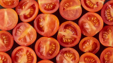 Cherry tomatoes. Slices on a black background Stock Photos