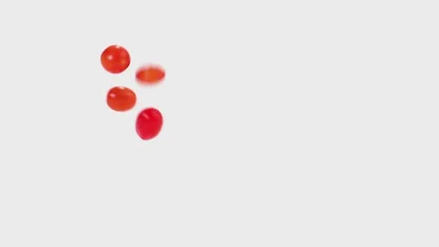 Cherry tomatoes tumble and fall in slow motion onto a white cyc Stock Footage 70683095