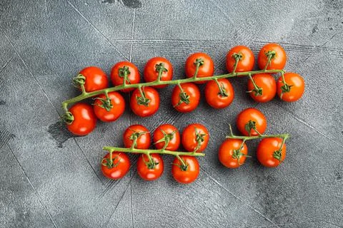 Cherry tomatoes on the vine, on gray stone background, top view flat lay Stock Photos