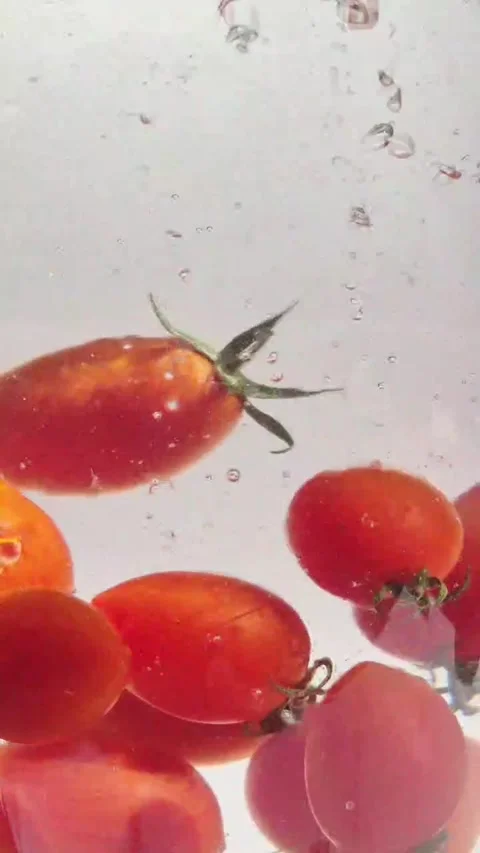 Cherry tomatoes in water in motion close-up on a light background Stock Footage 309998982