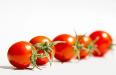 Cherry tomatoes on a white background are arranged in a row.selective focus Stock Photos