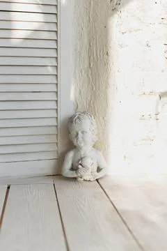 Cherubic Statue Basking in Sunlight by Rustic White Wall Stock Photos