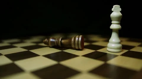 A chess board with a black background, a white king throws down the black king Stock Footage 58415064