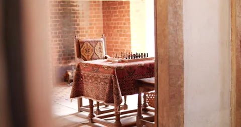 Chess board sitting on table in room focusing on chess pieces from doorway old Stock Footage 234590172