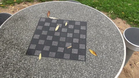 Chess board table with chairs and fallen leaves in park Stock Footage 55864443