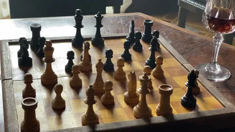 Chess dock with a started game of chess. glass half filled with red wine Stock Footage 232877509