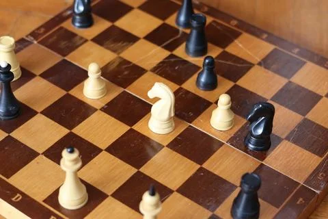 Chess game in progress with advanced tactics displayed on wooden board in a.. Stock Photos
