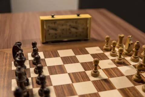 A Chess Game in Progress with a Classic Timer on a Polished Wooden Table Fe.. Stock-Fotos