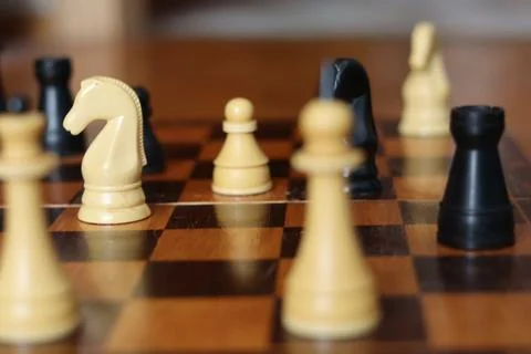 Chess game in progress with yellow and black pieces on a wooden board durin.. Foto stock