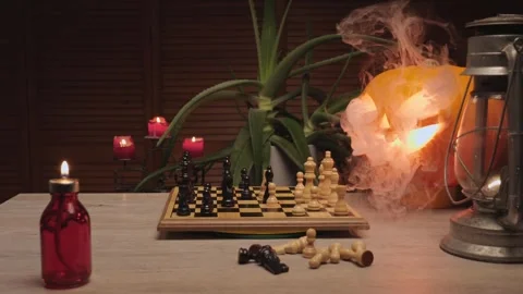 Chess game on table beside glowing smoking jack-o’-lantern, cozy Halloween Stock Footage 317225700