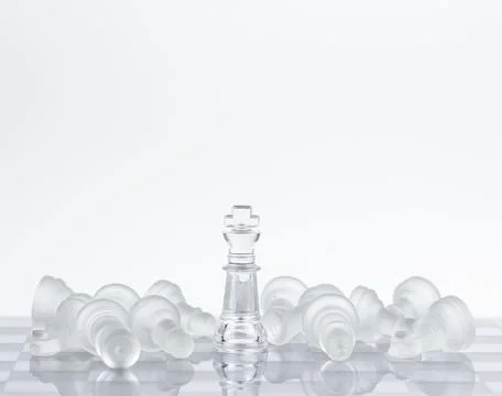 Chess on a glass table, pieces lying around the queen. Фото