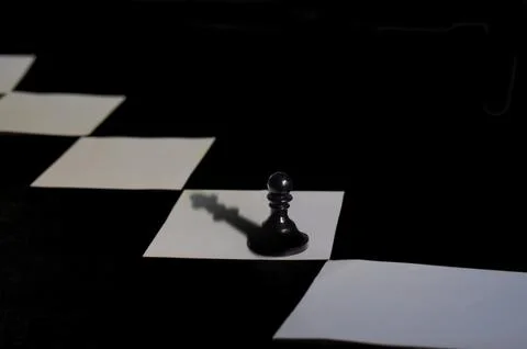 A chess pawn with a queen shadow. Stock Photos
