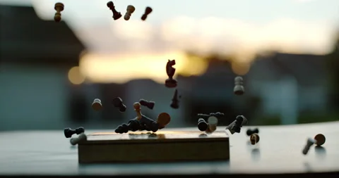 Chess Pieces fall onto chess board with sunset behind Video stock 247092558