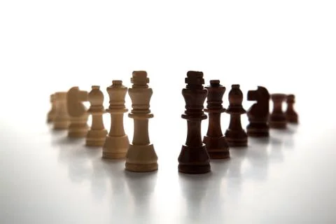 Chess pieces lined up in a row on a gray Stock-Fotos