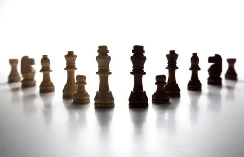 Chess pieces lined up in a row on a gray Stock Photos