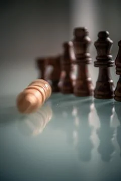 Chess pieces lined up on a table white and black with fallen king representin Stock Photos