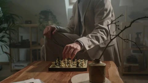 Chess player adjusts watch while sitting in a cozy room during a match Stock Footage 319958101