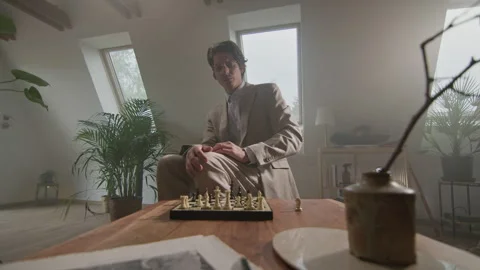 Chess player in a coat thinks strategically in a cozy room setting Vídeos de archivo 319956344