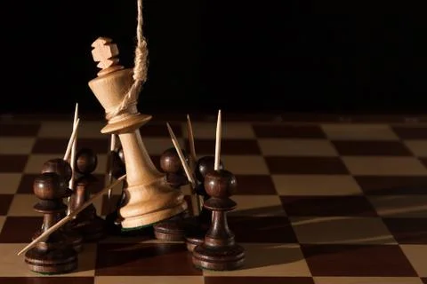 Chess. White king on the hinge loop lynch among the black figures on the ches Stock Photos