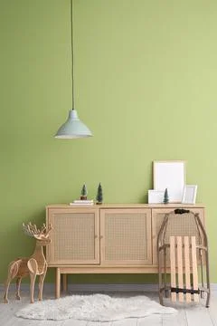 Chest of drawers with frames, Christmas decor and sled near green wall in roo Stock Photos