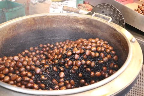 Chestnuts are roasted in a roasting machine. Stock Photos