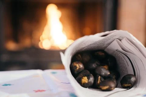 Chestnuts inside a cone with the fireplace in the background. Making roasted  Stock Photos
