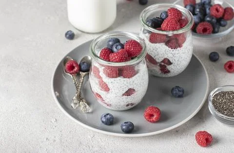 Chia pudding with blueberry and raspberry in glass jars on gray background... Stock Photos