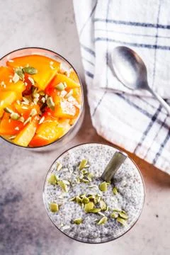 Chia pudding with persimmon and pumpkin seeds in glasses, gray background Foto stock