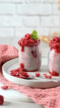 Chia seed pudding with fresh raspberry compote in glass jars on a plate Stock Photos