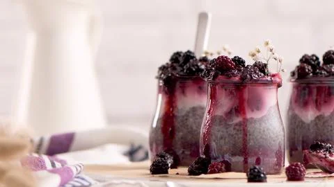Chia seed pudding jars layered with blackberry compote and cream Stock Photos